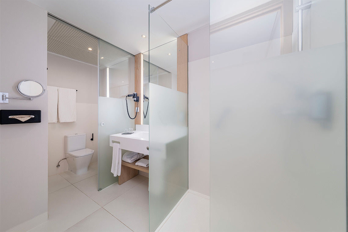 Bagno moderno con doccia in vetro, lavabo e WC.