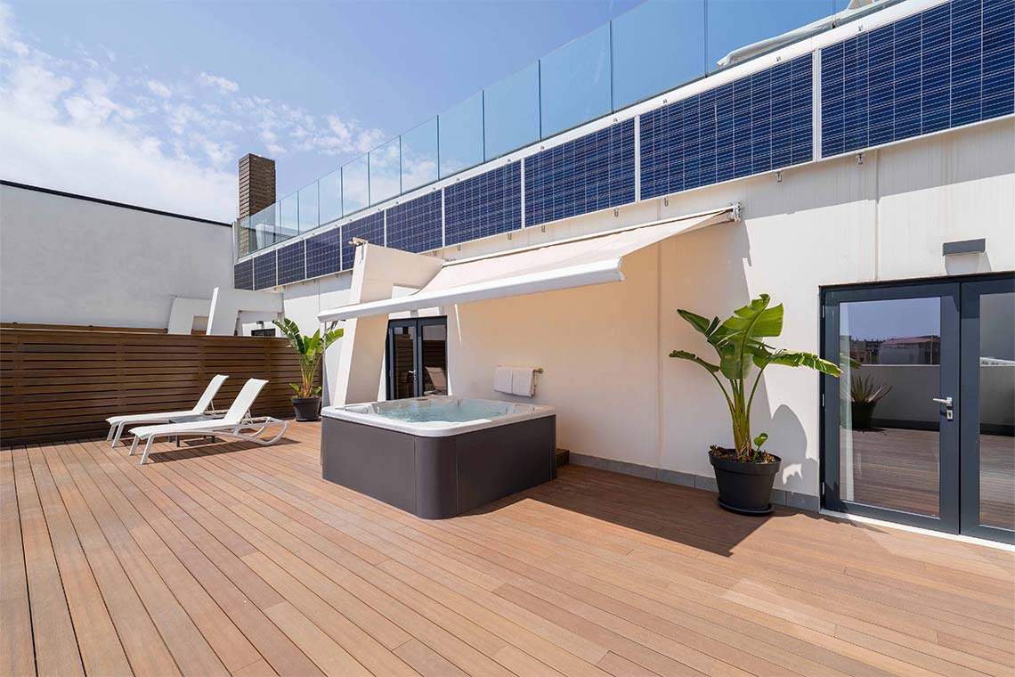 Terrazza con jacuzzi, lettini prendisole e pannelli solari.
