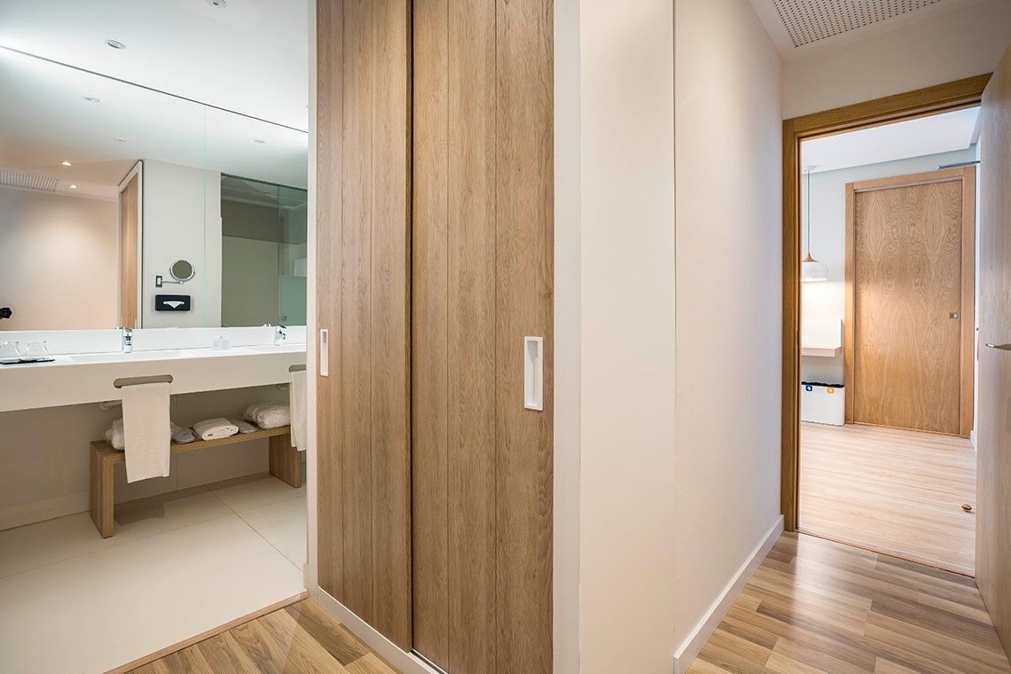 un pasillo que conduce a un baño con un lavabo y un espejo