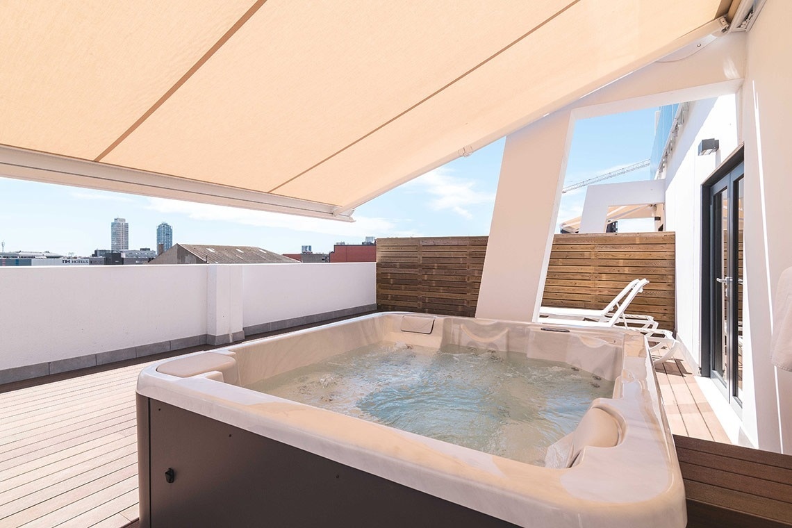 una bañera de hidromasaje en una terraza con un toldo