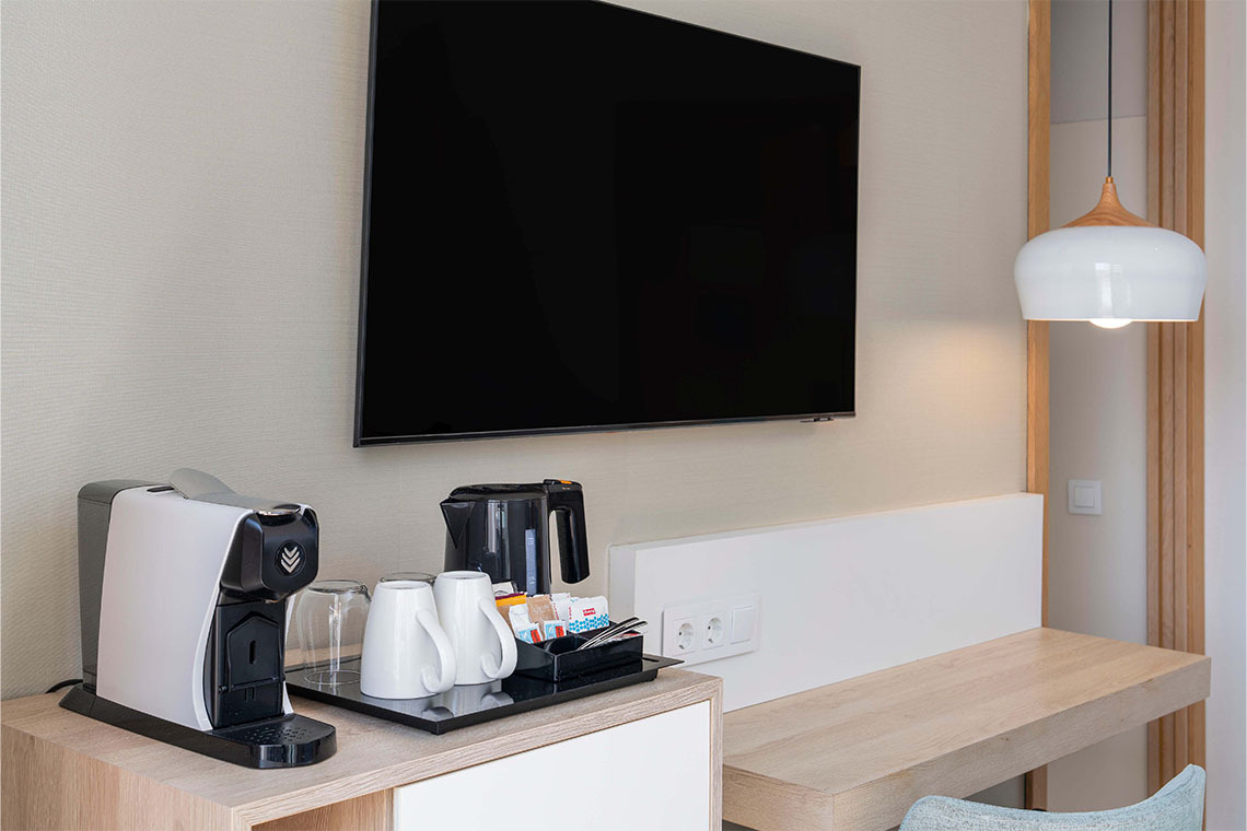 Macchina da caffè e bollitore in camera con TV e lampada a sospensione.