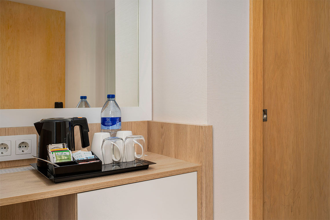 Amenidades de cortesía en la habitación de hotel, incluyendo ZT: Golden Barcelona, tazas, hervidor y agua.