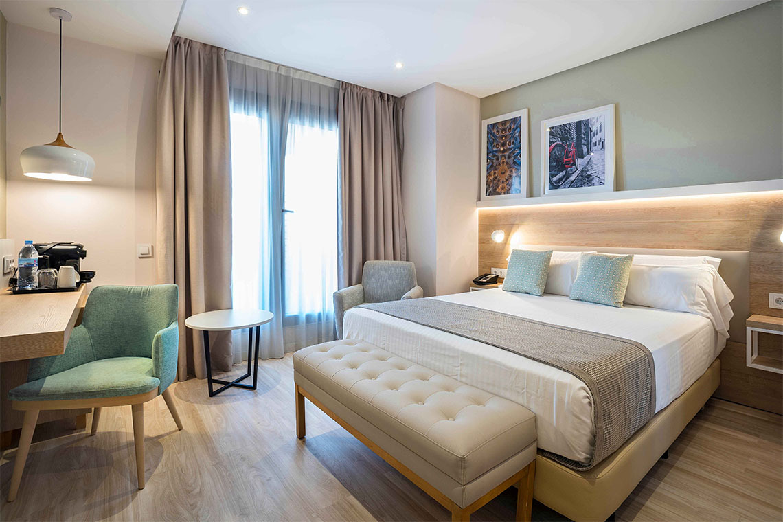 Habitación de hotel ZT: Golden Barcelona con cama queen, sillón y obras de arte.