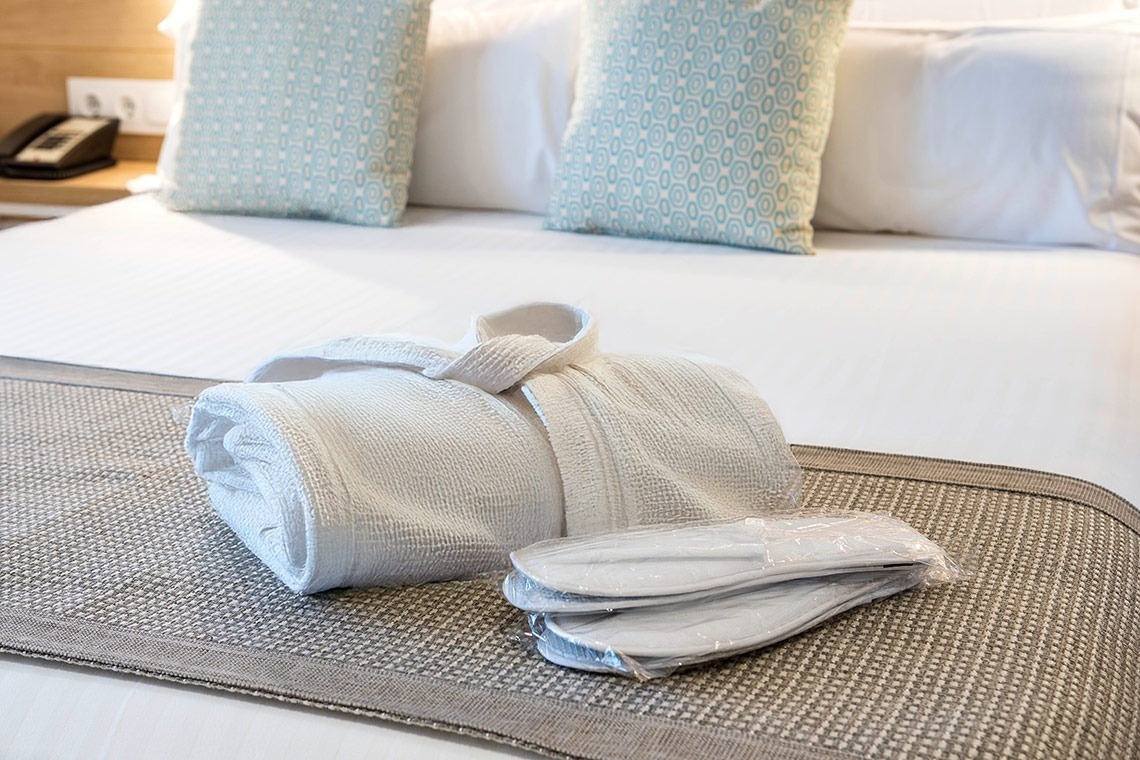 una habitación de hotel con una albornoz y zapatillas en la cama