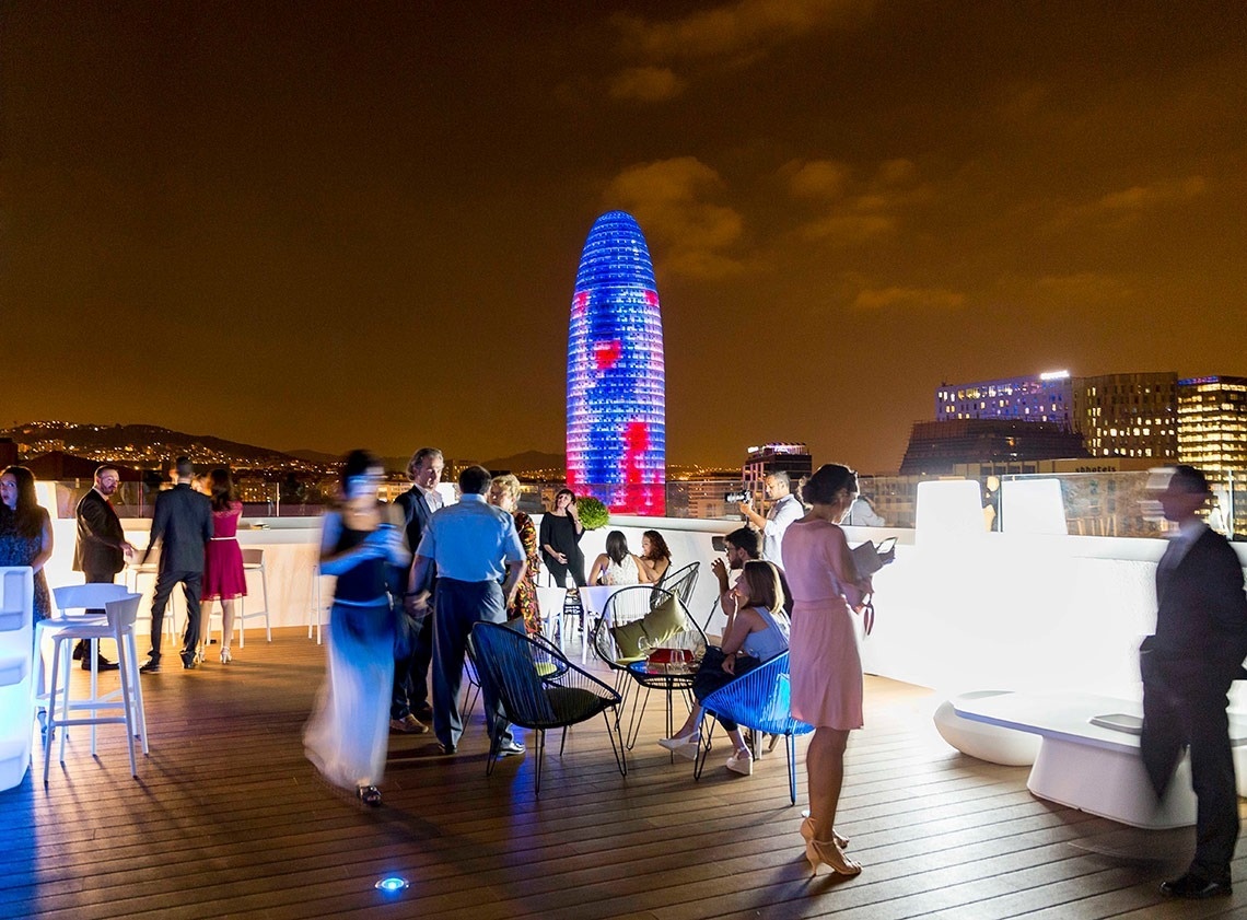 a group of people are gathered on a rooftop at night