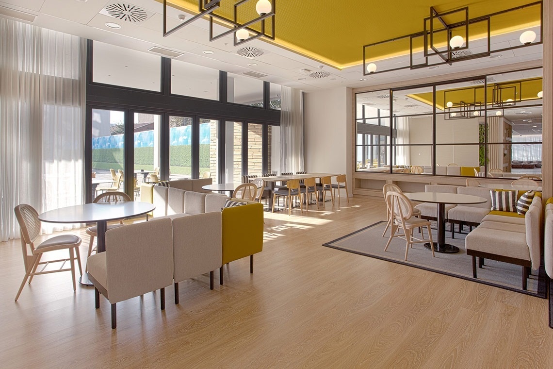 a restaurant with tables and chairs and a yellow ceiling