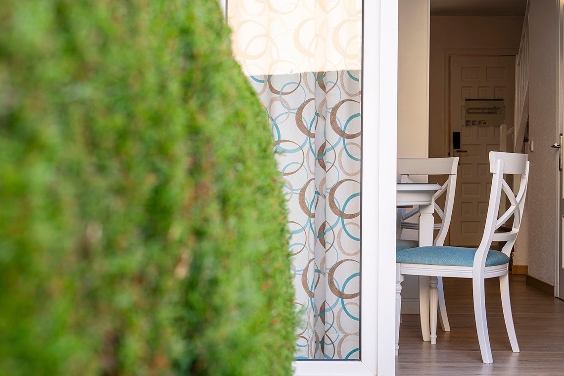 una puerta de vidrio que conduce a una mesa y sillas