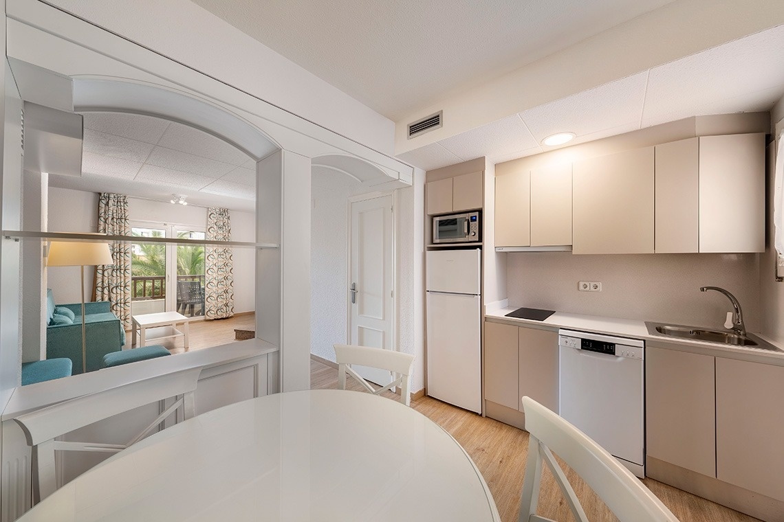 una cocina con una nevera y un microondas y una mesa y sillas