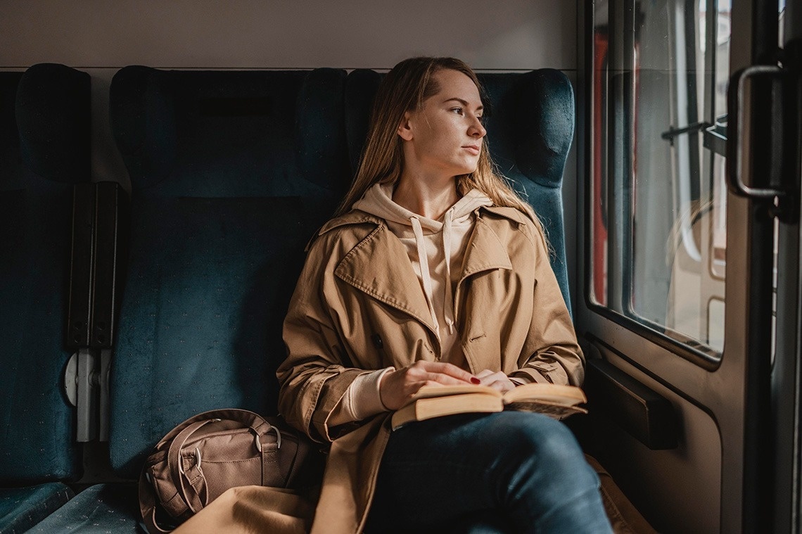 una mujer está sentada en un tren y leyendo un libro