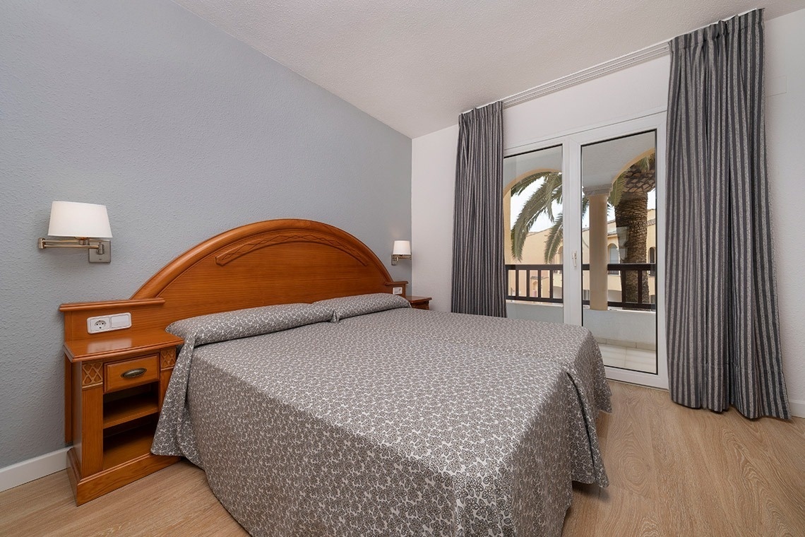 una habitación con una cama y una puerta que da a un balcón