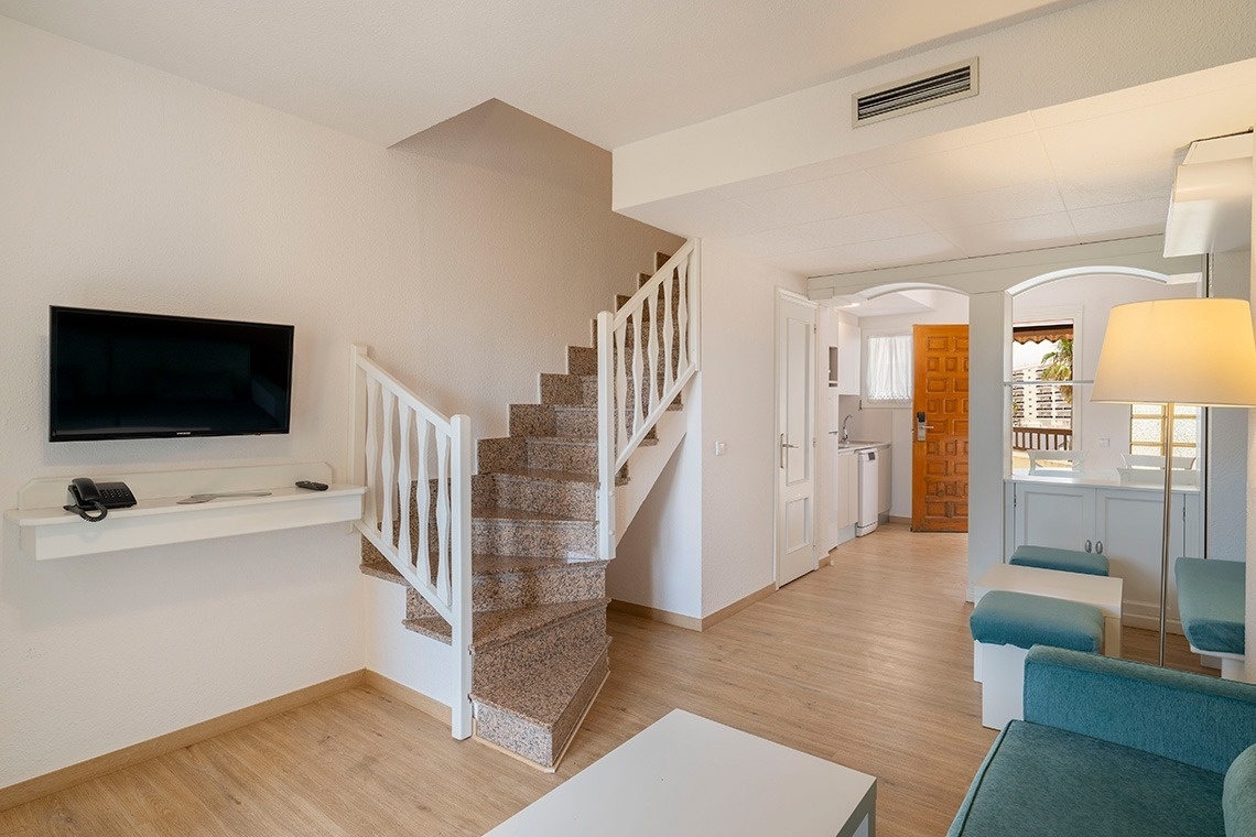 una sala de estar con escaleras y una televisión