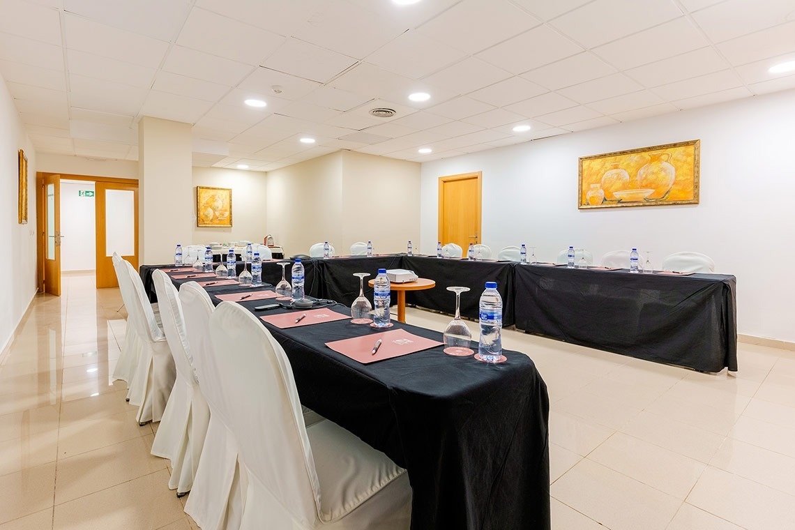 una sala de conferencias con mesas y sillas y botellas de agua