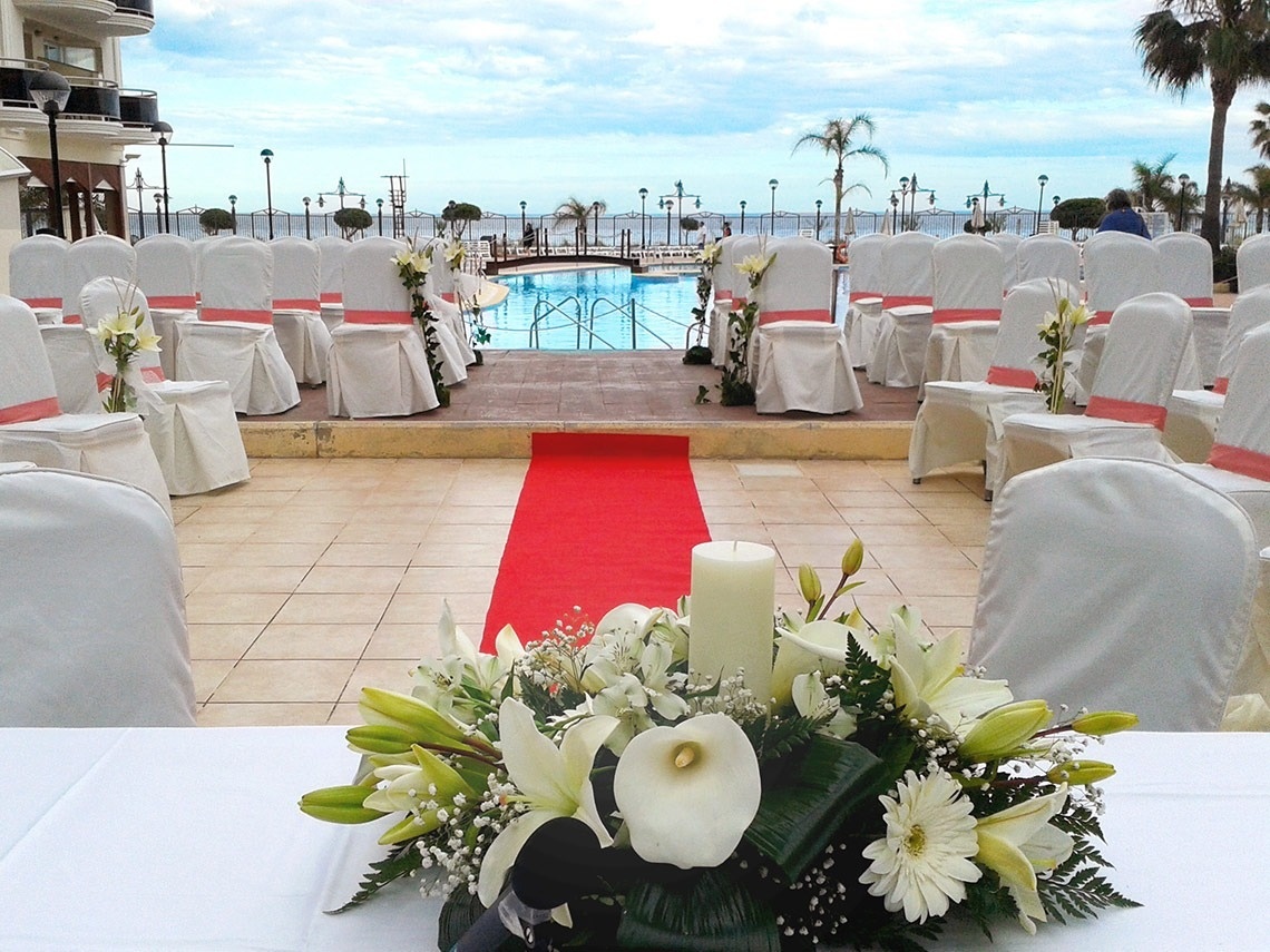 una alfombra roja conduce a una ceremonia de boda al aire libre