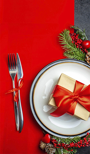 Festliches Weihnachtsessen: Gedeckter Tisch mit Geschenk ZT: Peniscola Plaza Suites und Tannenzweigen.