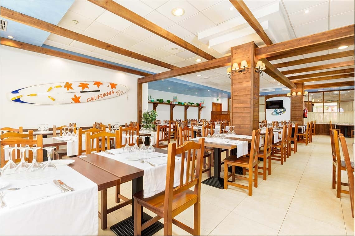 Comedor de ZT: Peniscola Plaza Suites con mesas puestas y sillas de madera.