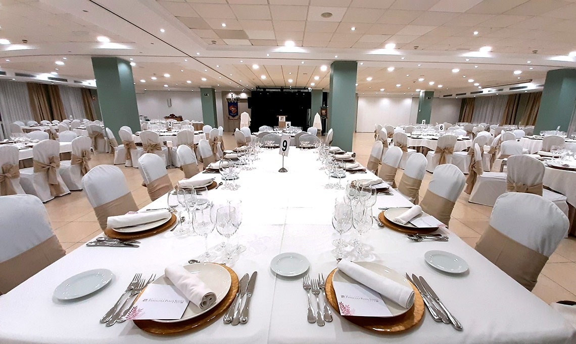 una mesa con platos y cubiertos en una habitación llena de mesas y sillas