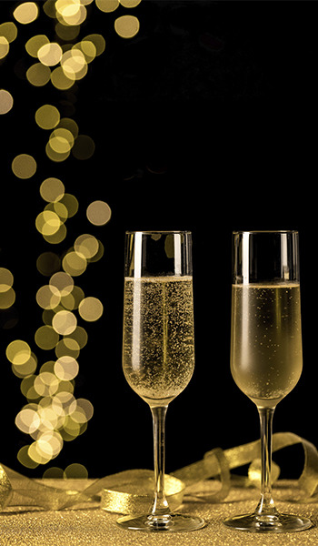 Zwei Champagnergläser mit funkelnden Blasen auf glitzerndem Untergrund, perfekt für eine ZT: Peniscola Plaza Suites-Feier.