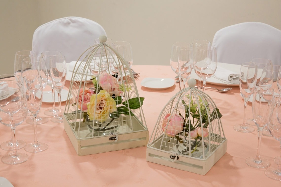 dos jaulas llenas de flores están sobre una mesa