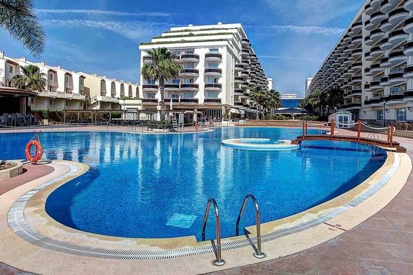 una gran piscina rodeada de edificios y palmeras