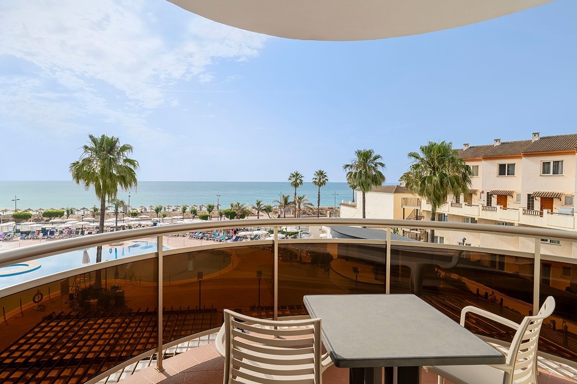 una mesa y sillas en un balcón con vistas al océano