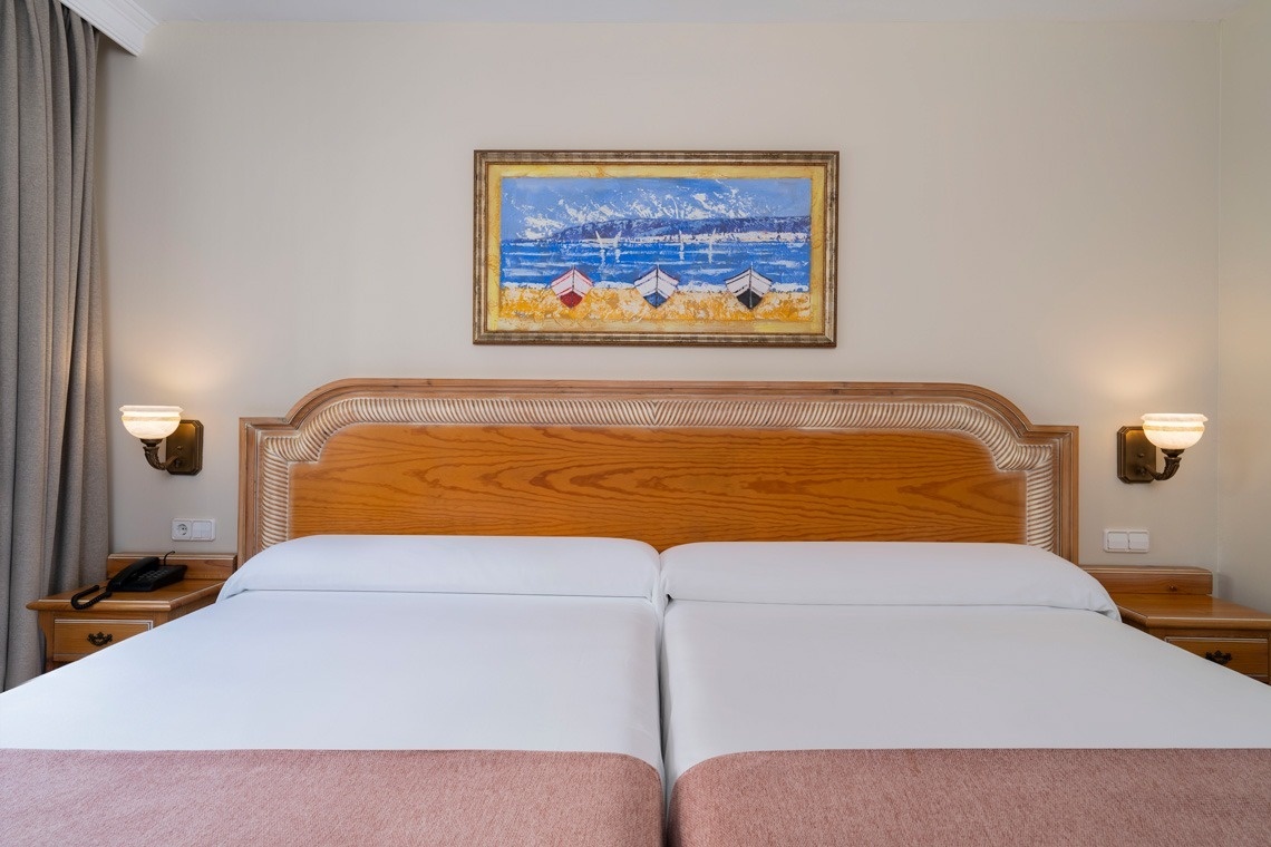 una habitación con dos camas y una pintura en la pared