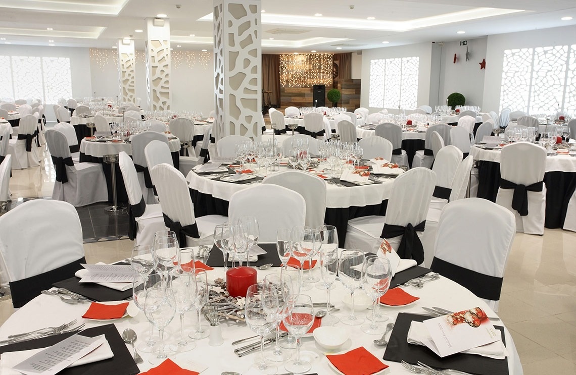 una habitación llena de mesas y sillas con una vela roja en la mesa