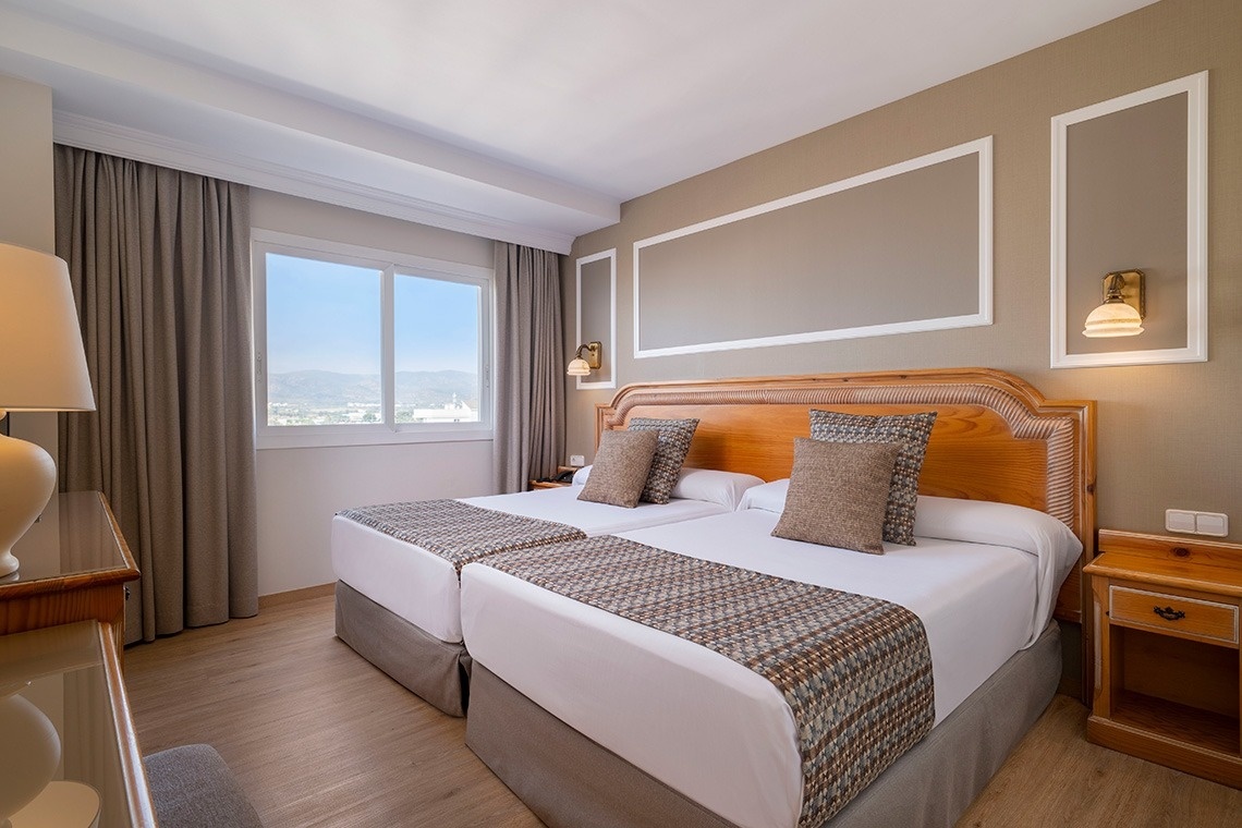 una habitación de hotel con dos camas y una ventana