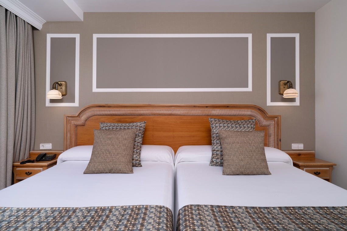 una habitación de hotel con dos camas y una cabecera de madera