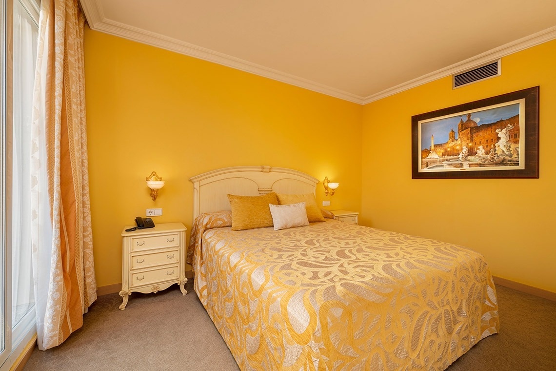 una habitación amarilla con una cama y un cuadro en la pared