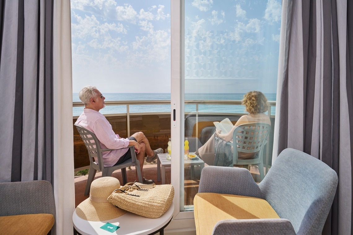 un hombre y una mujer están sentados en un balcón mirando al océano