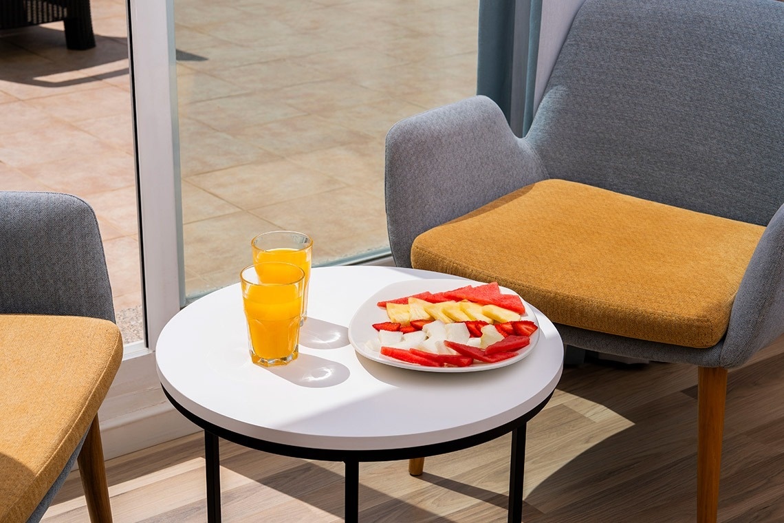 una mesa con un plato de frutas y un vaso de jugo de naranja