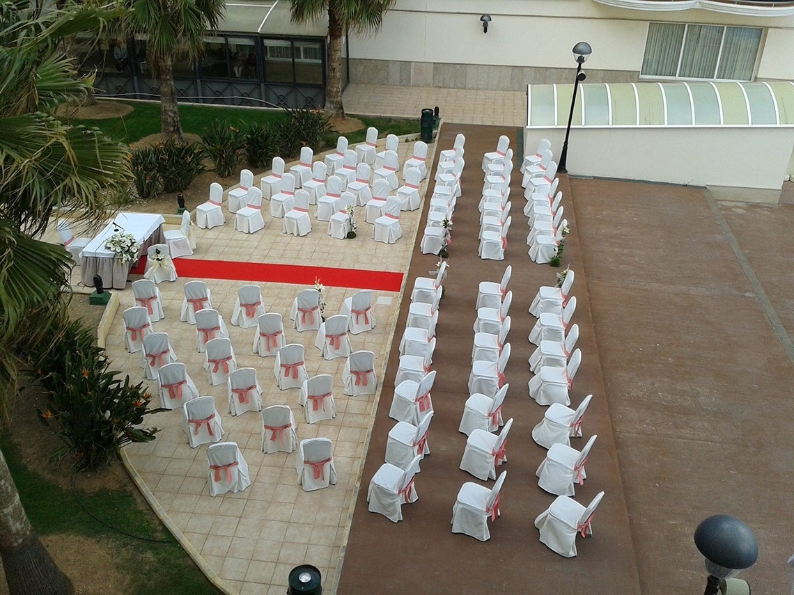 filas de sillas blancas con lazos rojos y una alfombra roja