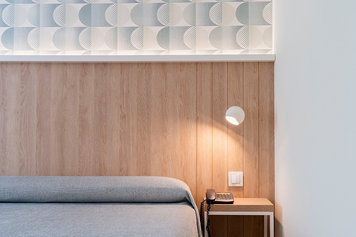 una habitación con una cama y una mesita con un teléfono y una lámpara