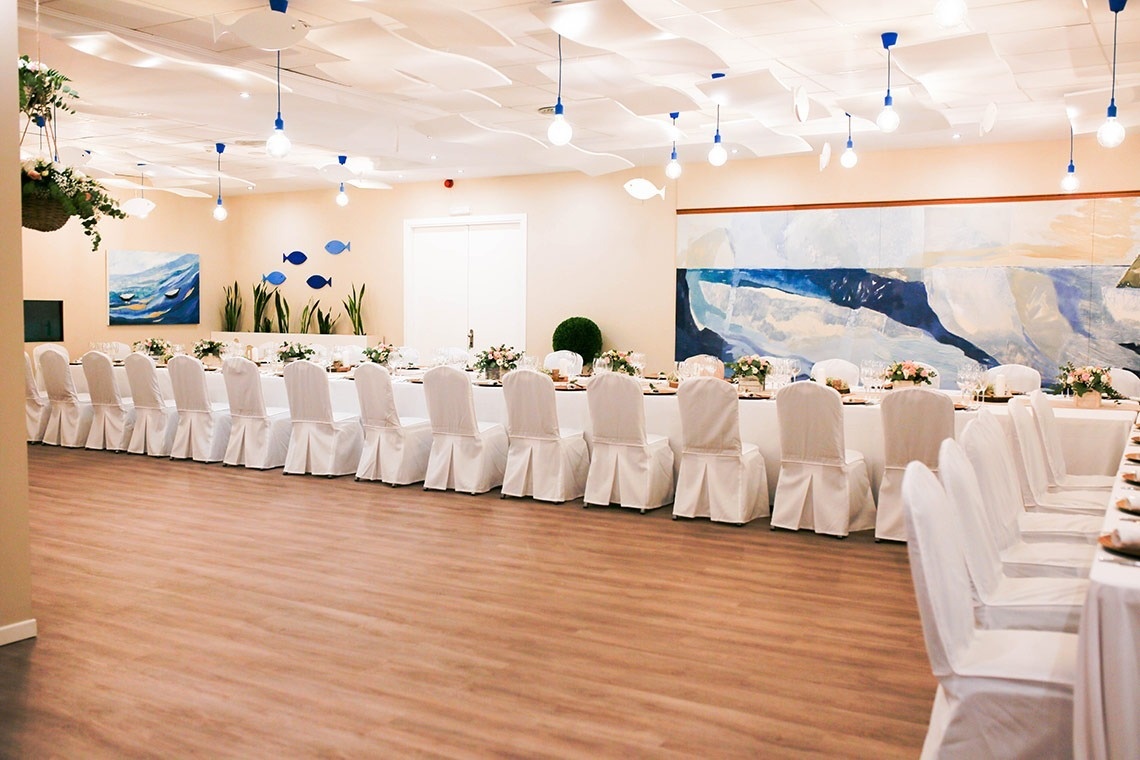una mesa larga con sillas blancas y una pintura en la pared