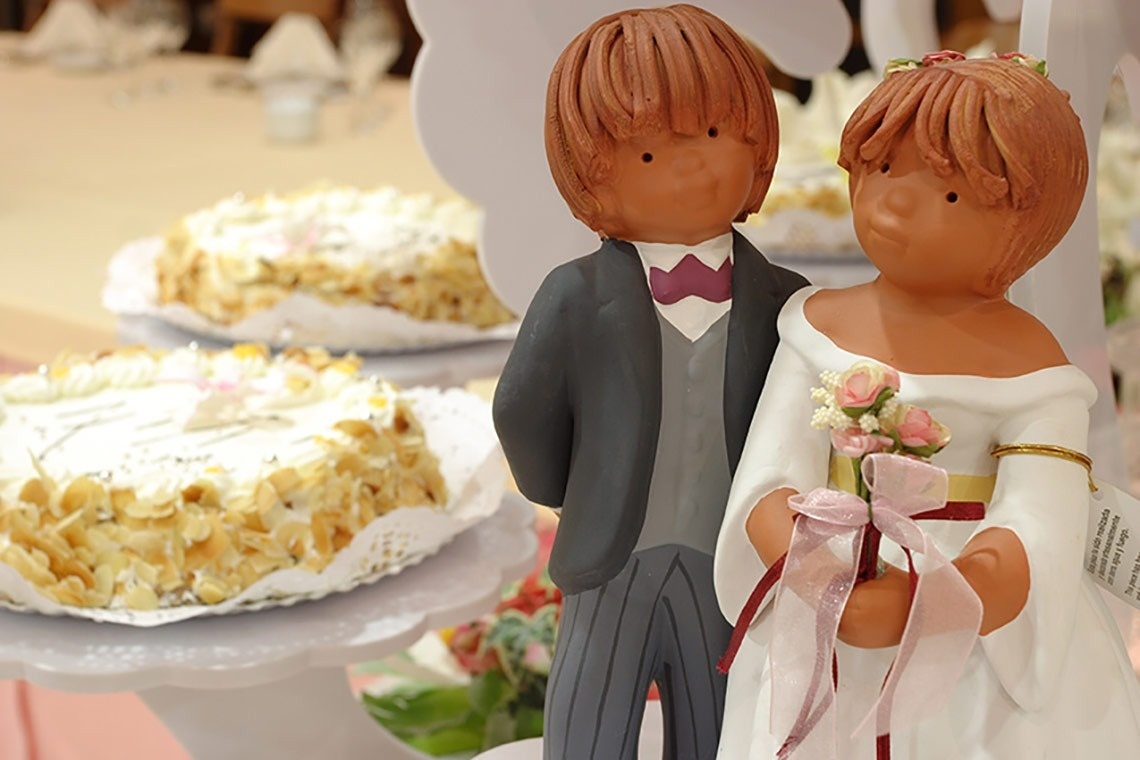 una novia y un novio están parados frente a un pastel de bodas