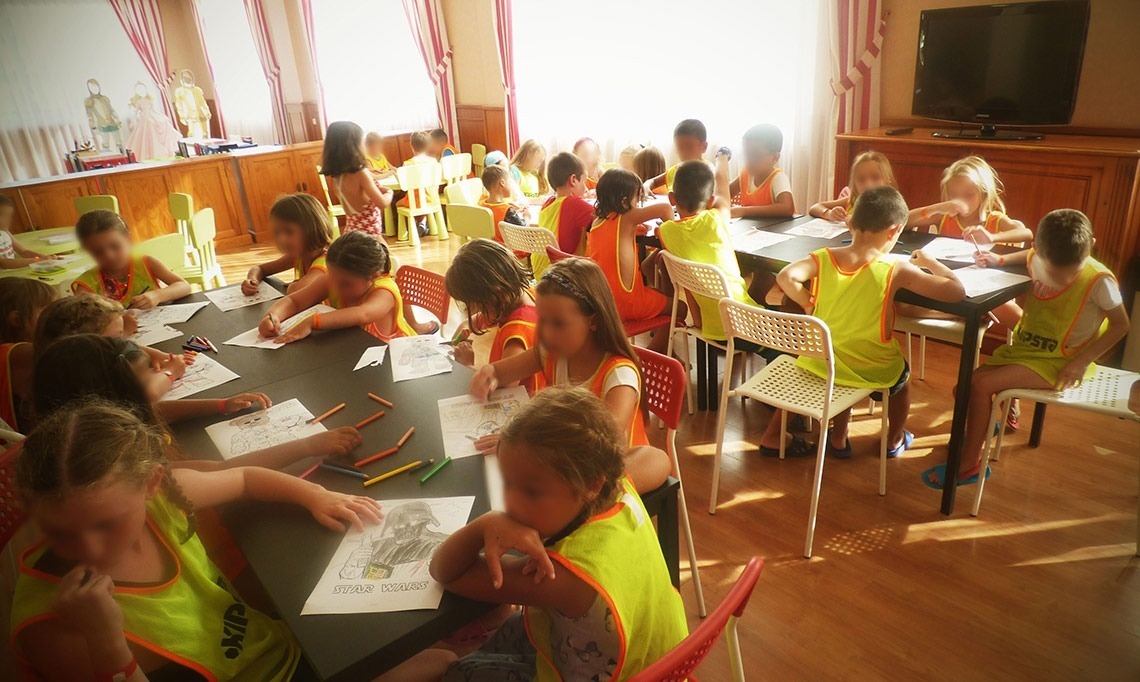 un grupo de niños están sentados en una mesa y dibujando