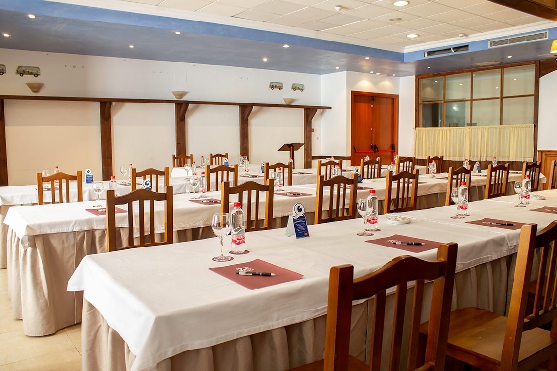 una habitación llena de mesas y sillas con botellas de agua y copas