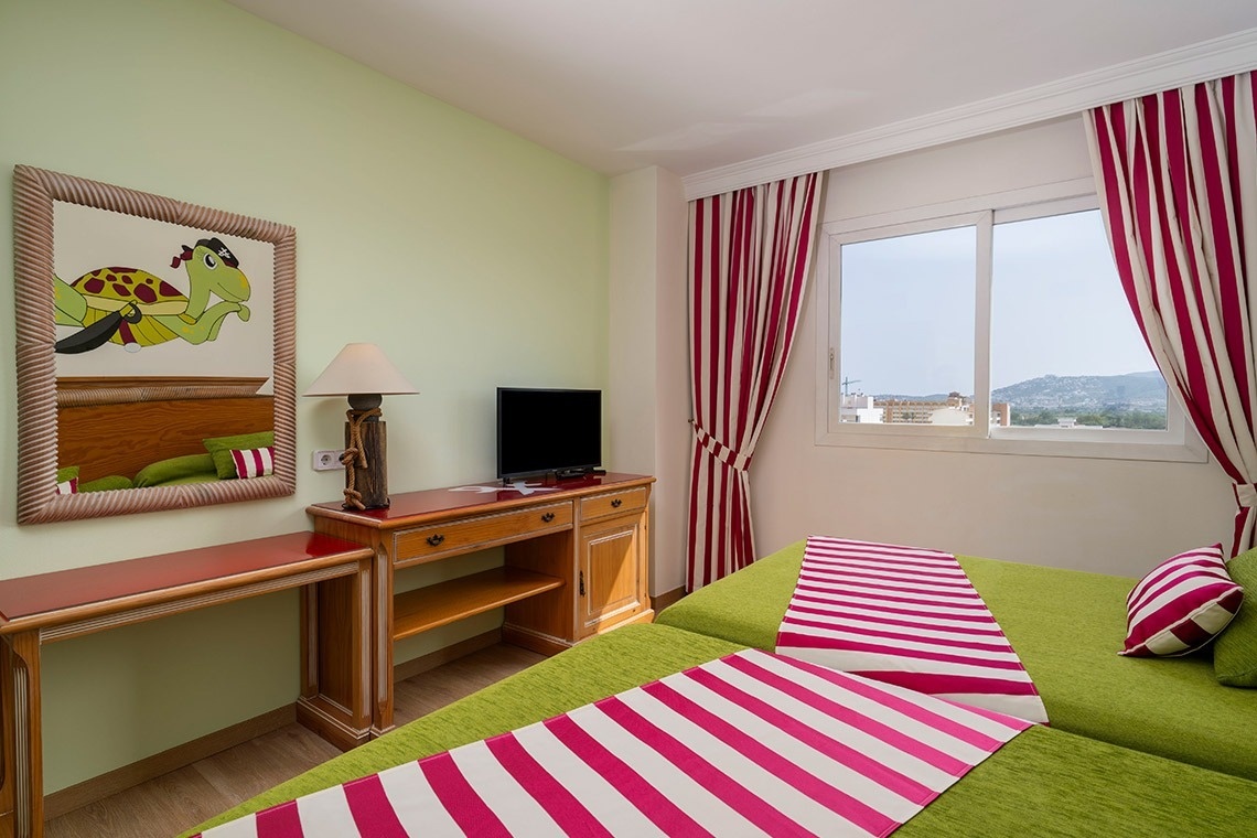 una habitación con una cama verde y una televisión