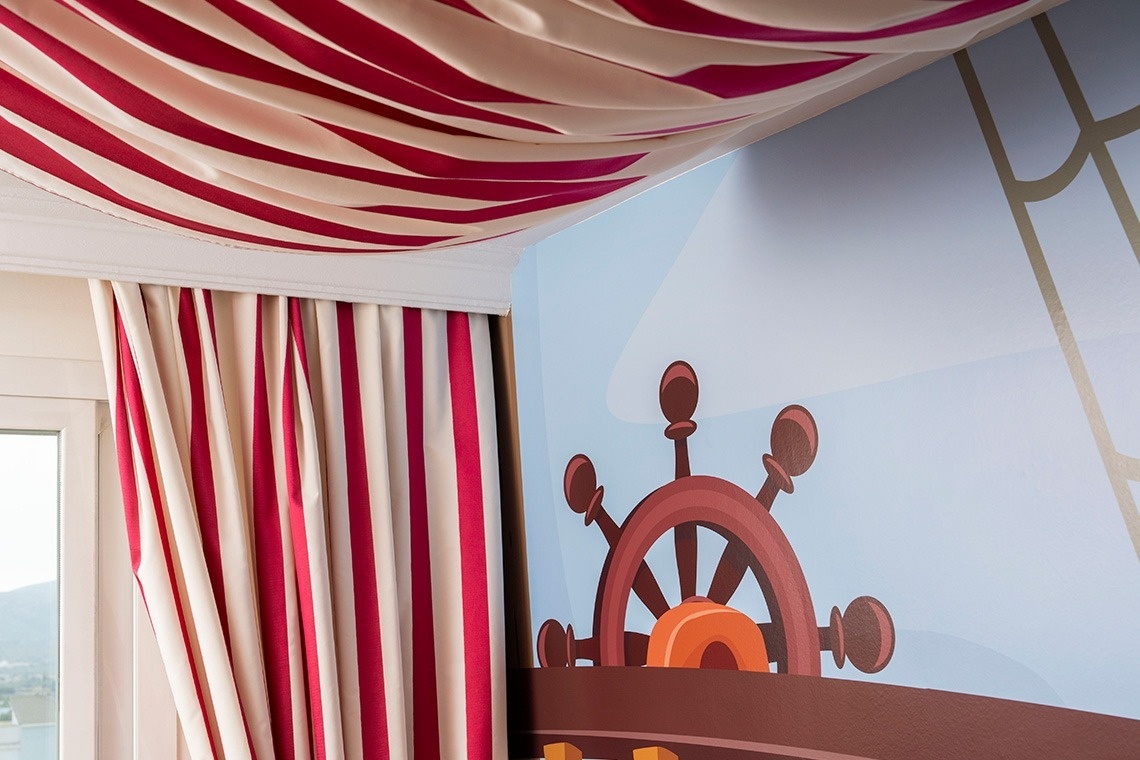 una habitación para niños con un timón de barco en la pared