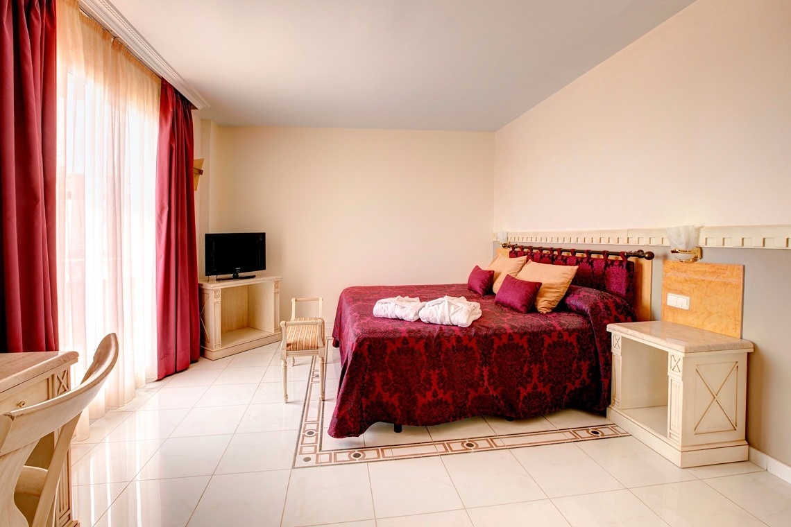 una habitación con una cama roja y una televisión