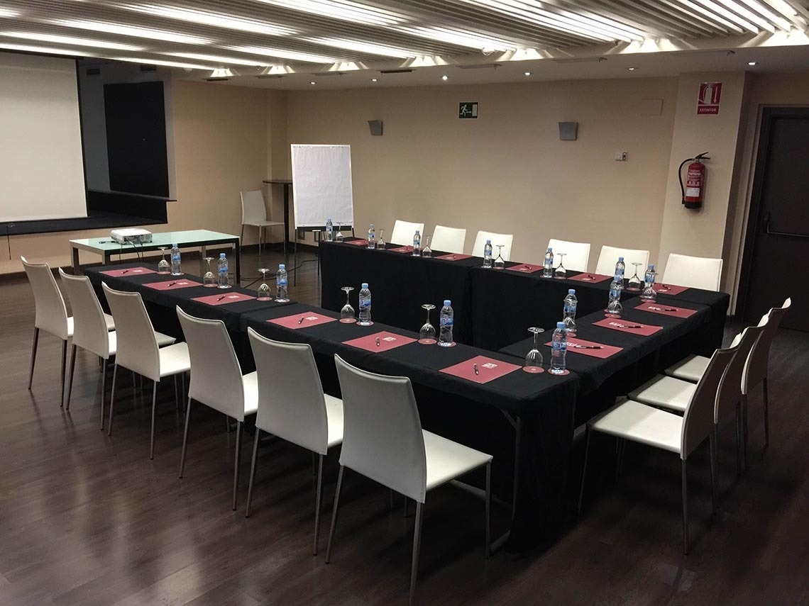 una sala de conferencias con mesas y sillas y un extintor en la pared