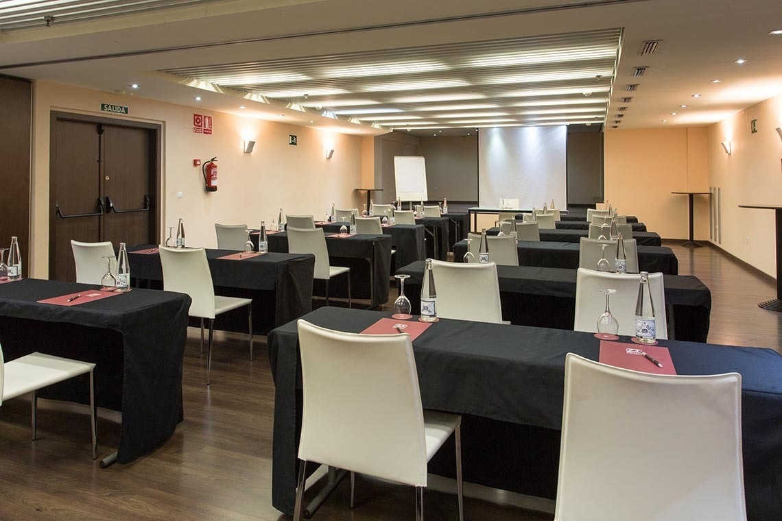 una sala de conferencias con mesas y sillas y un extintor en la pared