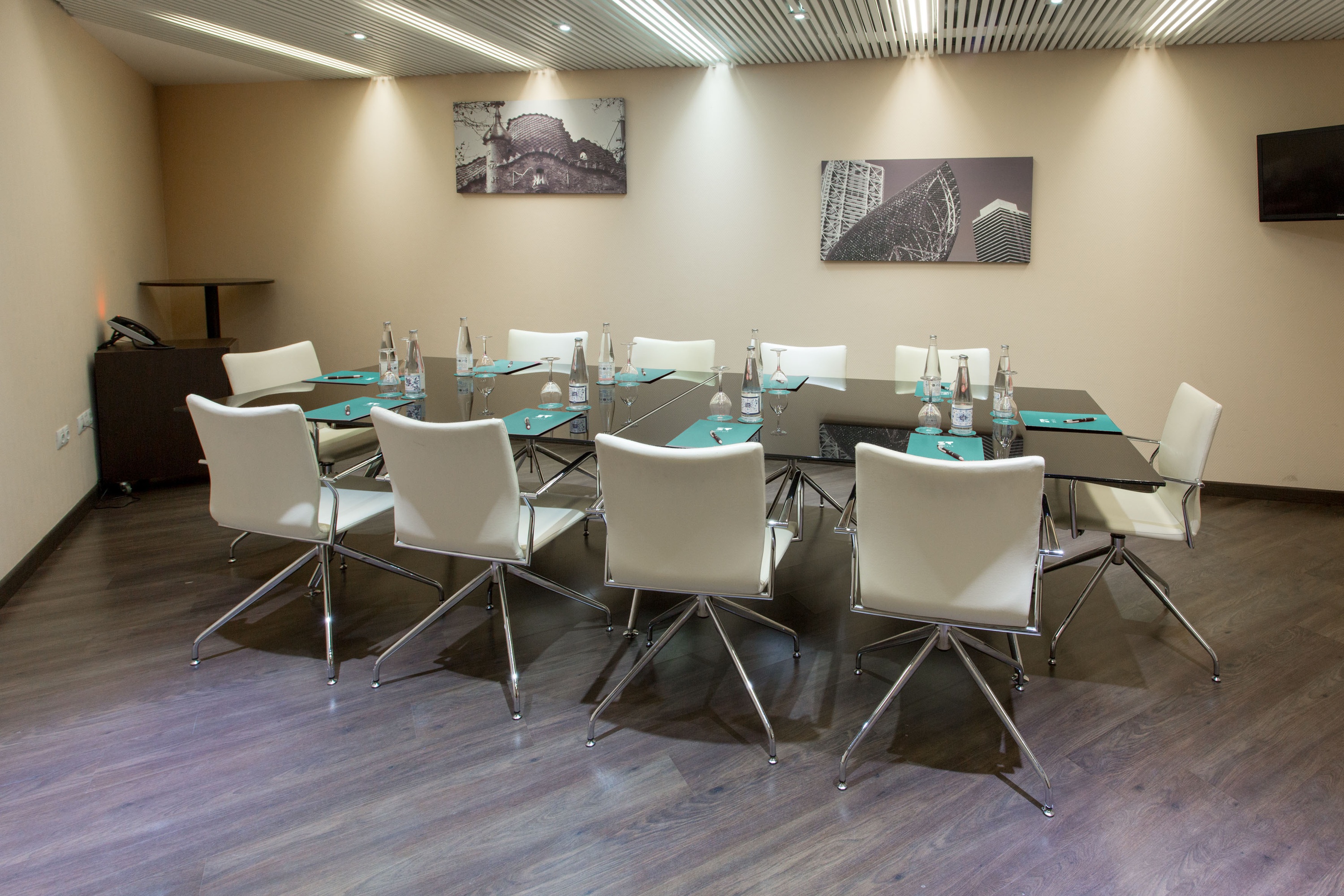 Conference room at ZT: Villa Olimpica with U-shaped tables, white chairs, and projection screen.