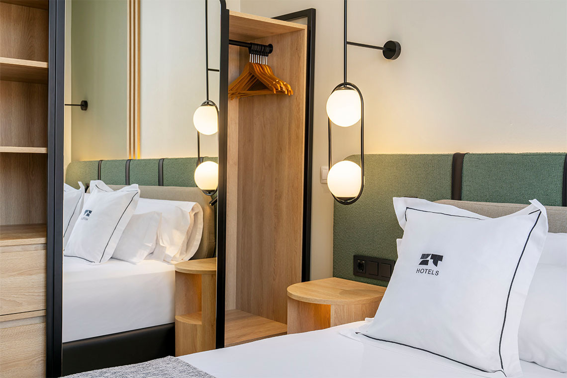 Habitación de hotel moderna con cama, armario abierto y lámparas colgantes. ZT: Villa Olimpica