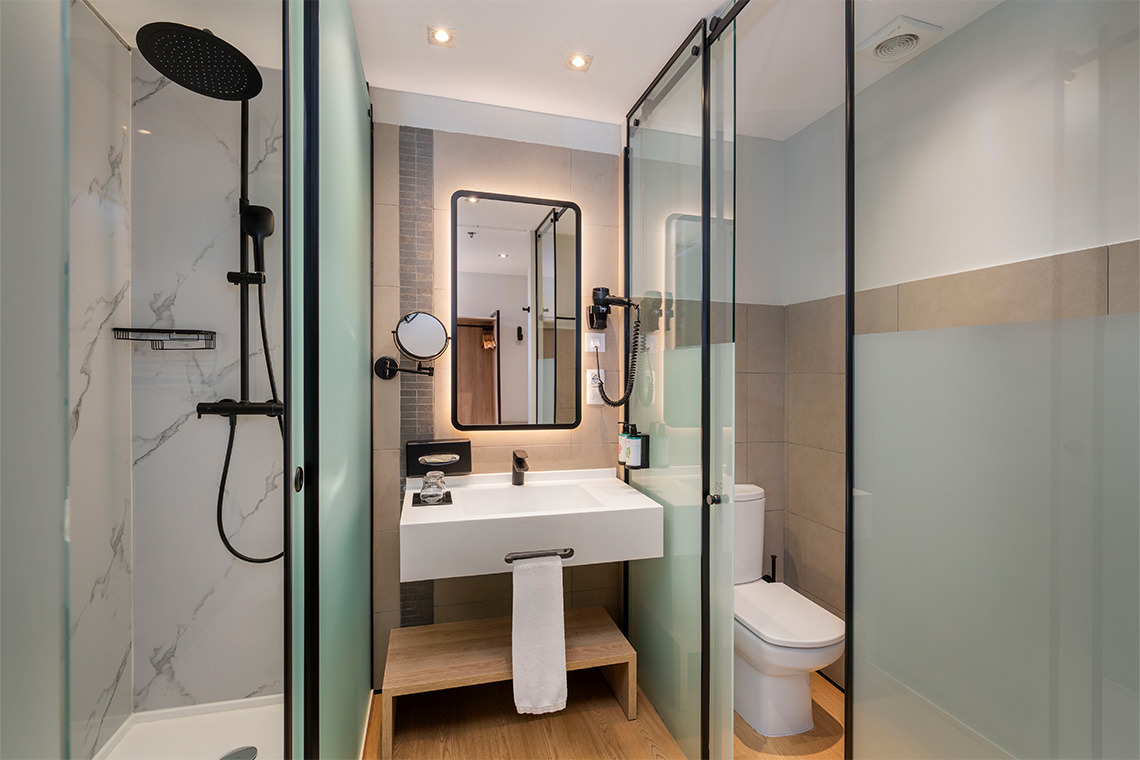 Baño moderno y elegante de hotel con ducha, lavabo e inodoro. ZT: Villa Olimpica