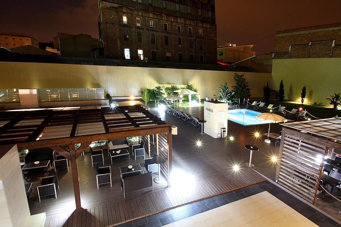 una piscina rodeada de mesas y sillas por la noche