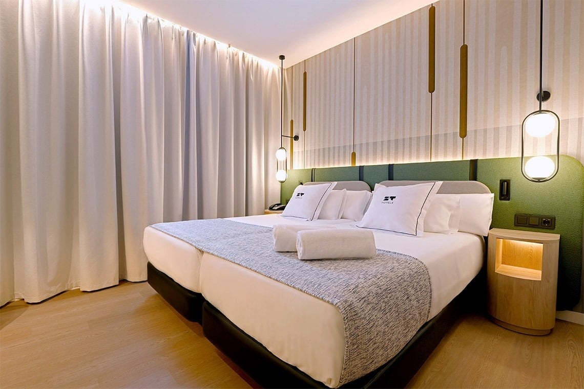 una habitación de hotel con dos camas y una cabecera verde