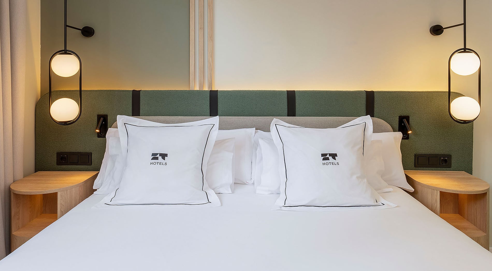 Cama de hotel con almohadas blancas, mesitas de noche de madera y lámparas modernas. ZT: Villa Olimpica