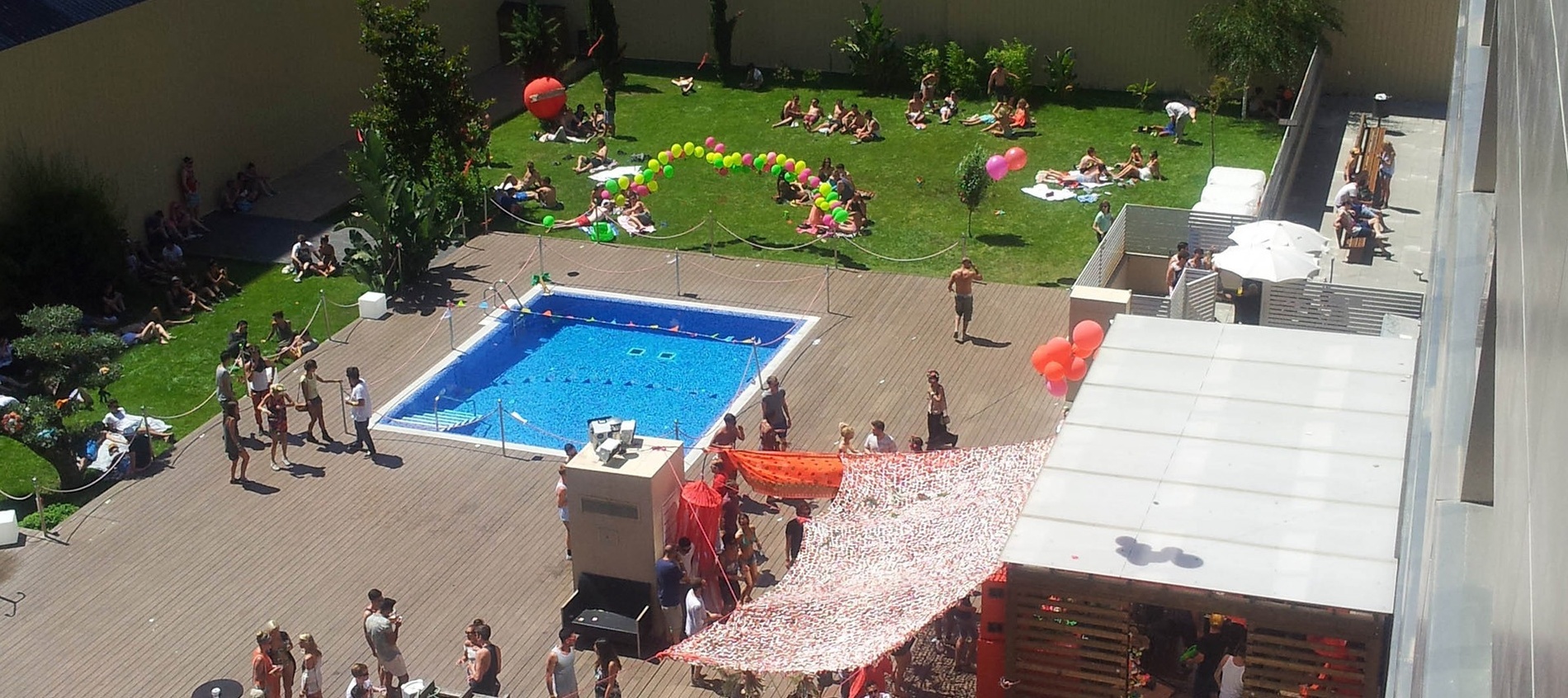 un grupo de personas se reúnen alrededor de una piscina rodeada de globos