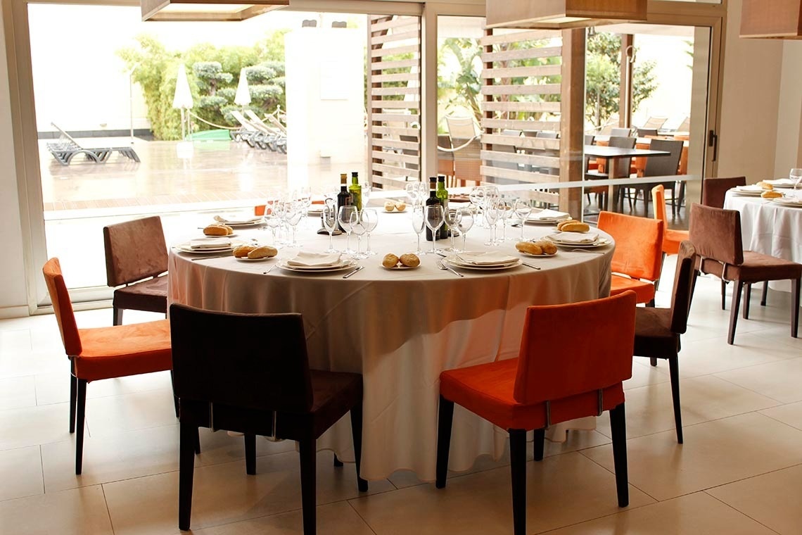 una mesa redonda con una mesa blanca y sillas naranjas